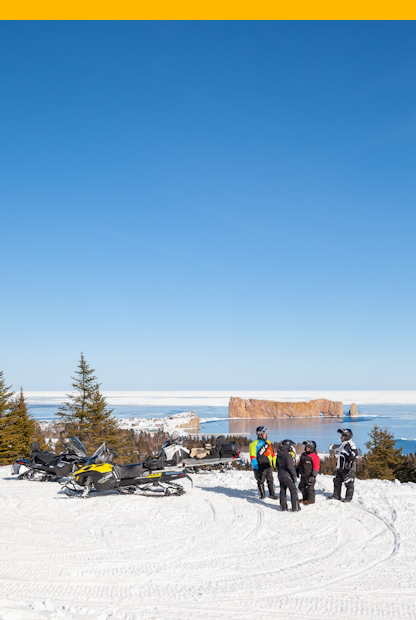 Snowmobilers in front of Percé Rock
